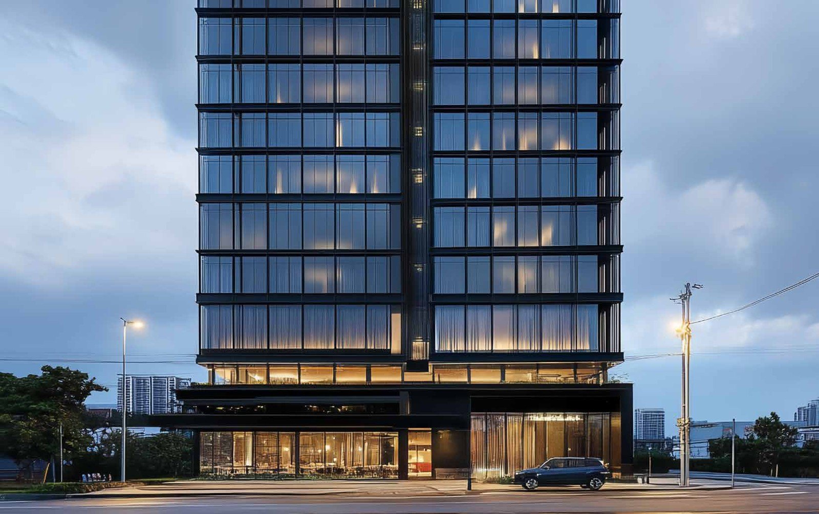 Black curtain-wall hotel tower lit at dusk
