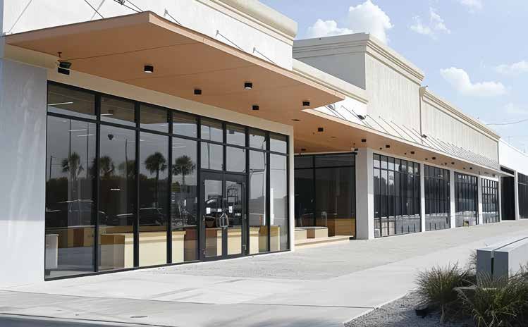 Retail row with black aluminum storefronts under a deep canopy