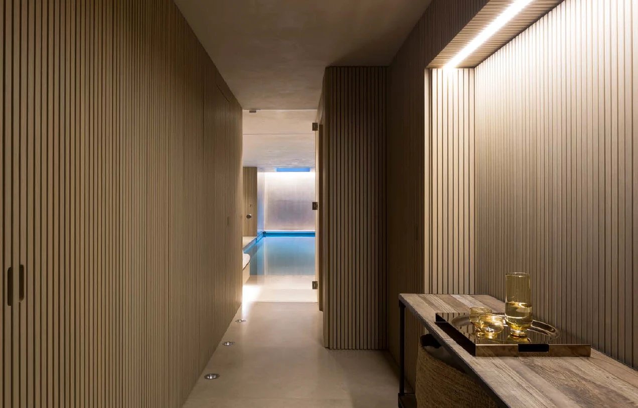 Slatted corridor leading to a glass-walled indoor pool