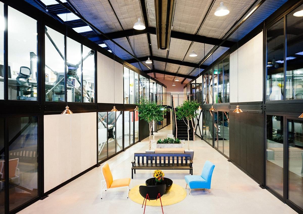 Two-storey black glass office fronts around a converted warehouse atrium