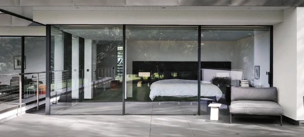 Slim-frame impact sliding glass wall opening a bedroom to the terrace