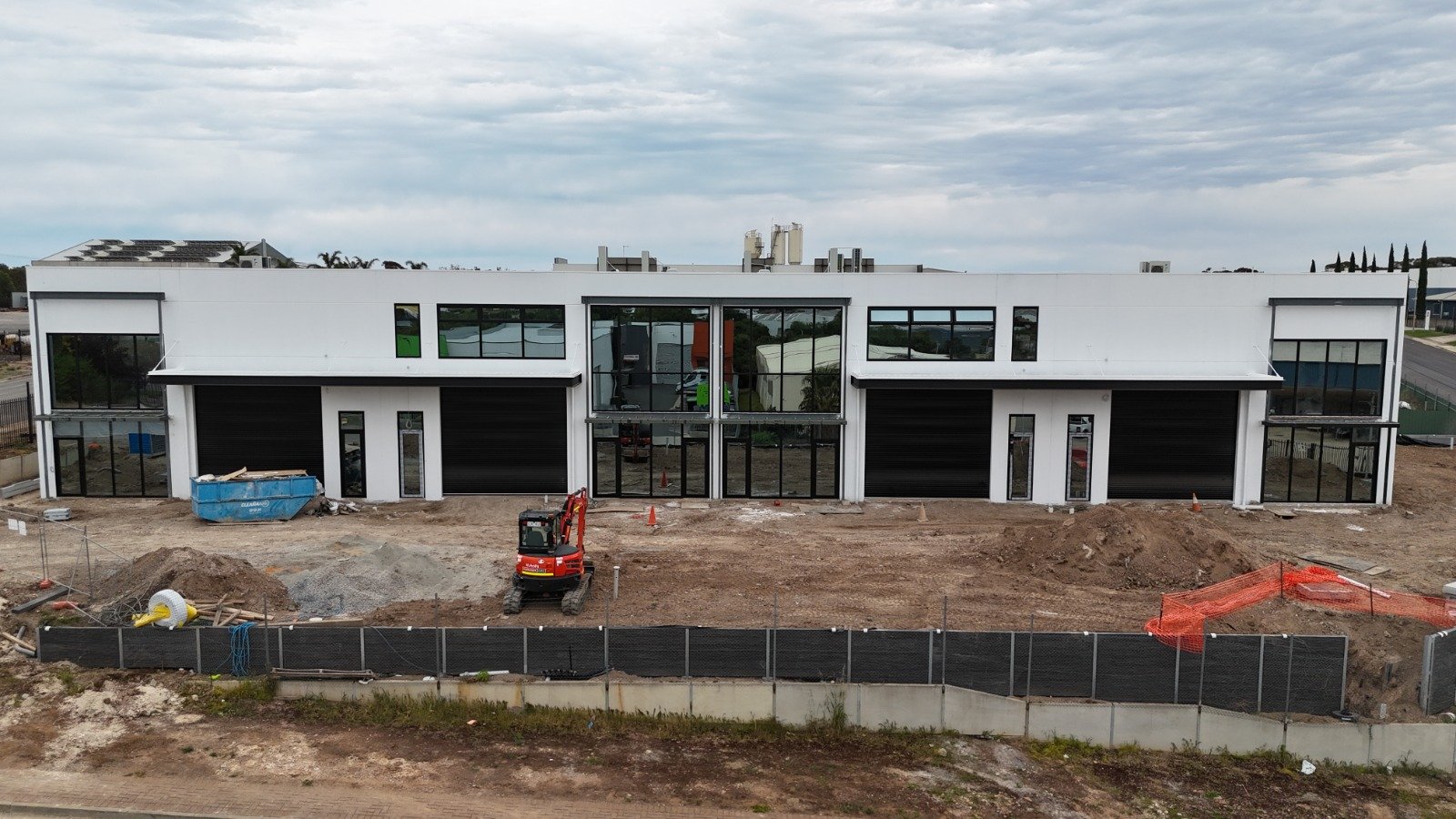 Row of commercial units with black storefronts and window walls