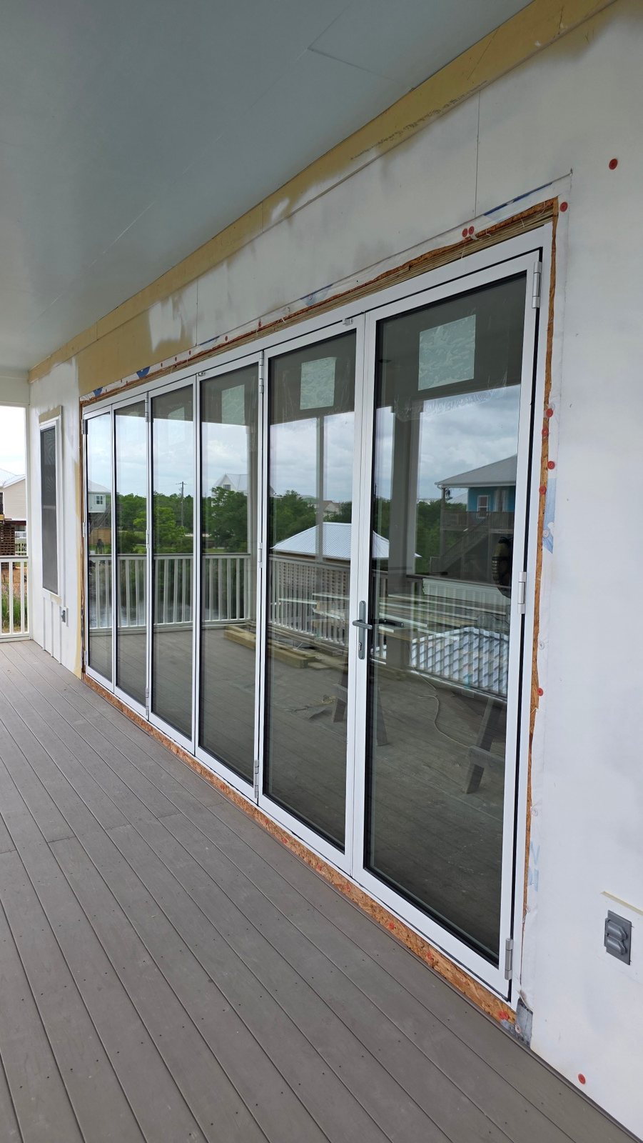White aluminum bifold doors along a coastal deck
