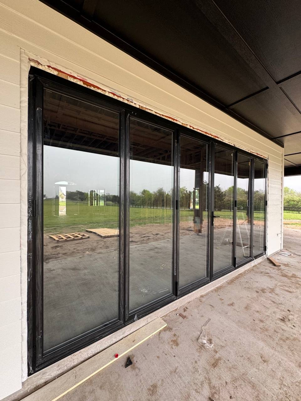 Black bifold door wall with a cream siding surround