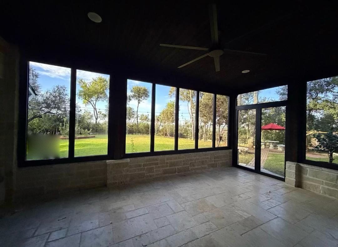 Black-framed sunroom glazing and French doors over a Hill Country lawn