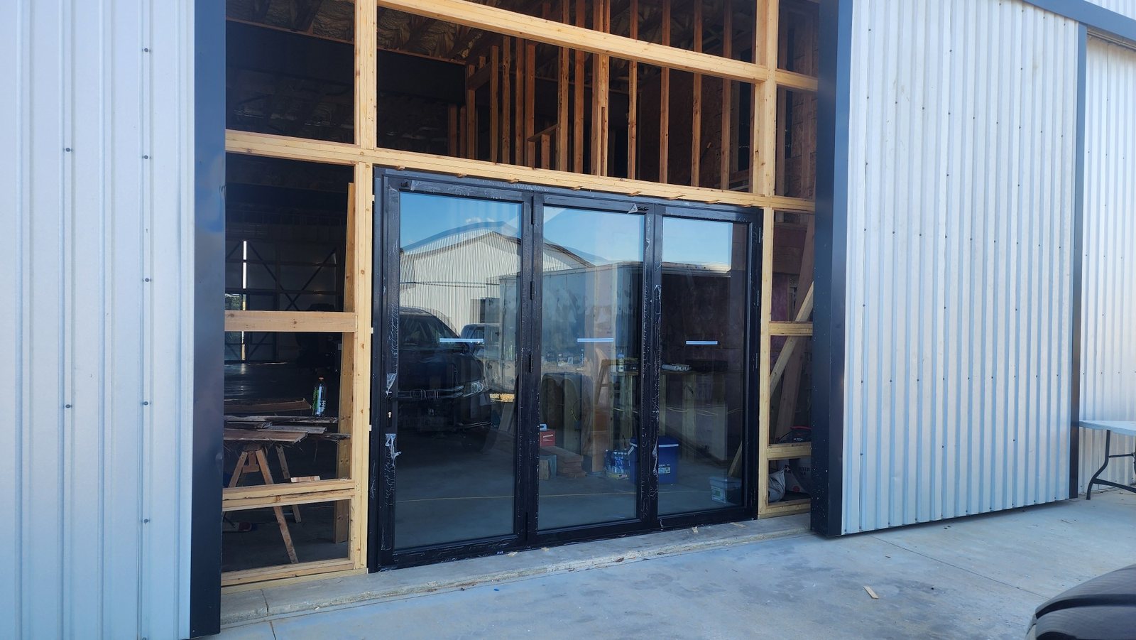 Three-panel black folding door in a steel workshop