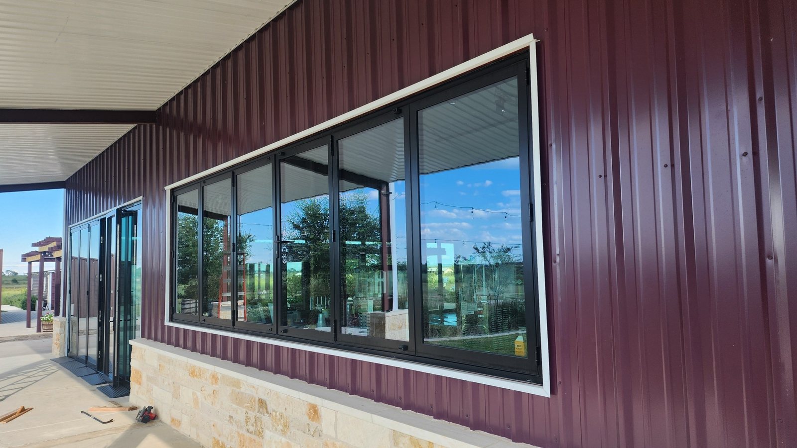 Black bifold window over a stone wainscot