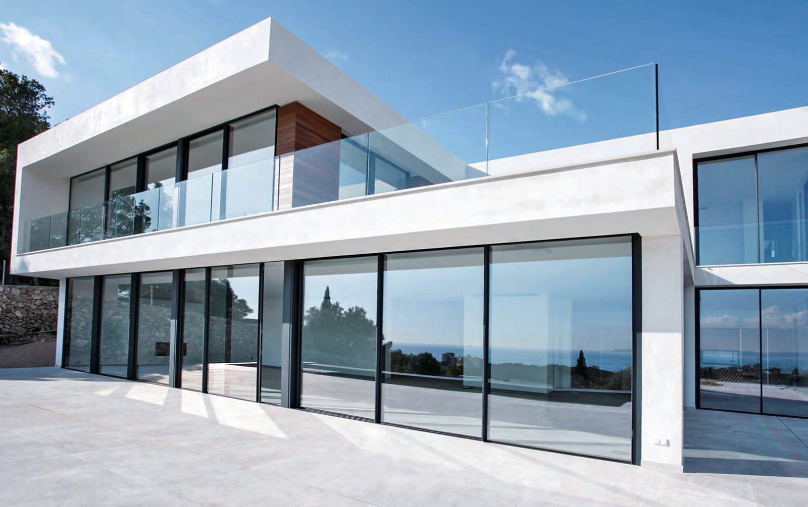 Two-storey white villa with black sliding glass walls