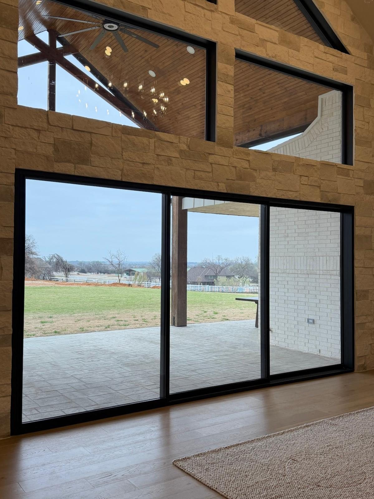 Black sliding doors and clerestory windows in a Texas stone great room