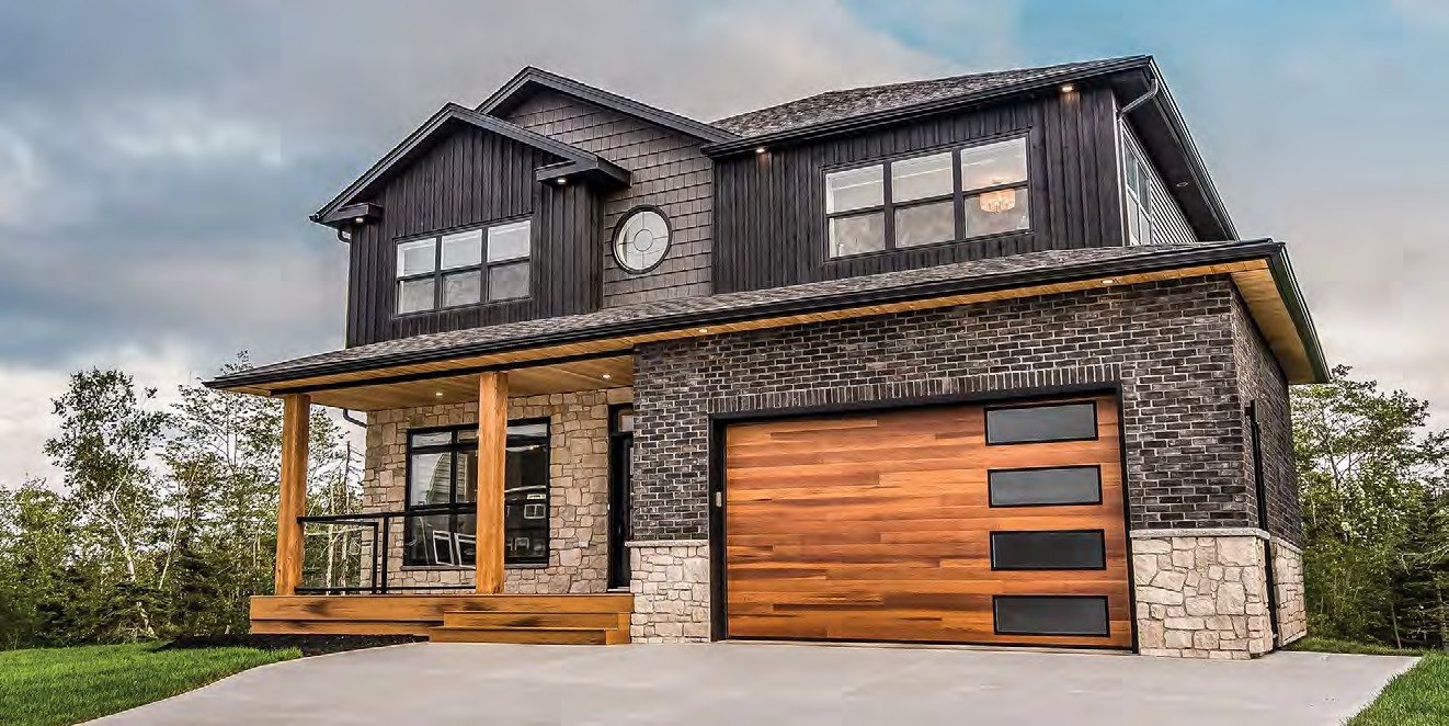 Woodgrain garage door with glass lites on a stone and shingle home