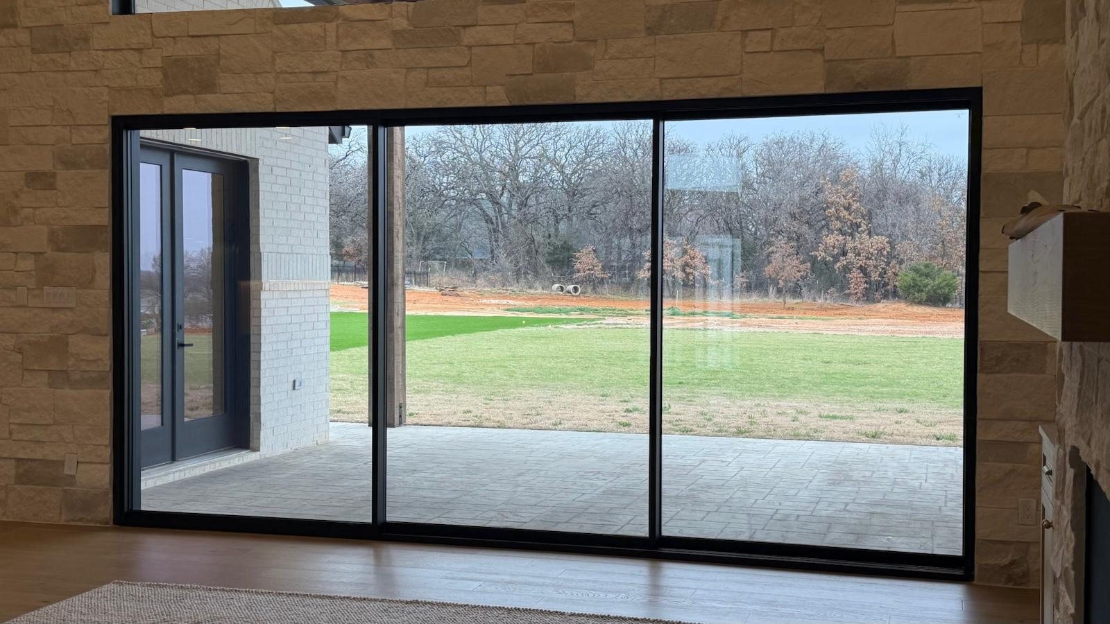 Three-panel black sliding door framing the patio and pasture