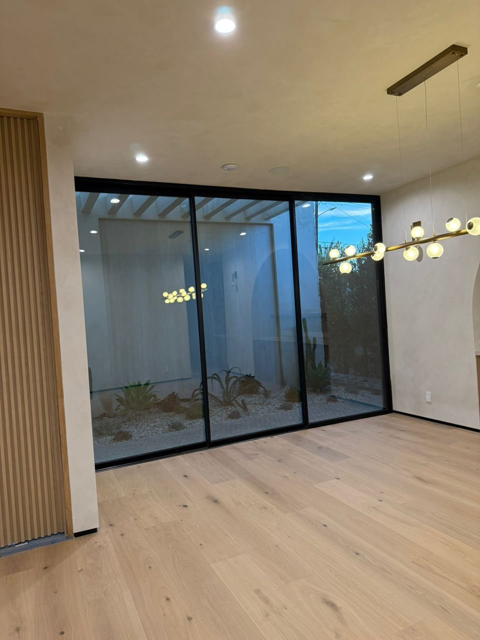 Black three-panel sliding glass wall onto a desert courtyard