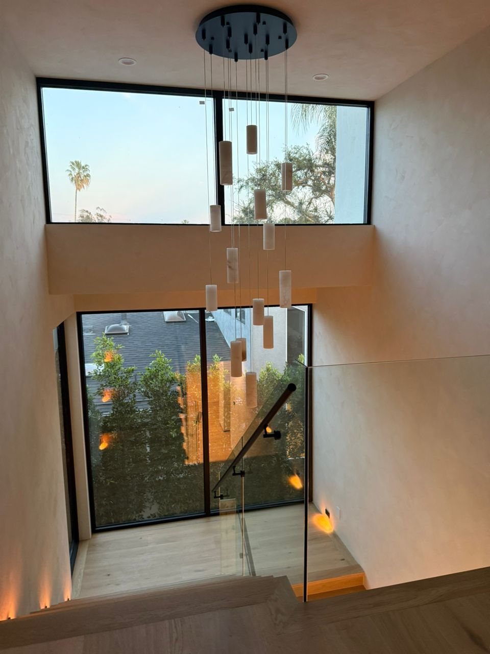 Two-storey black window wall lighting a stair hall
