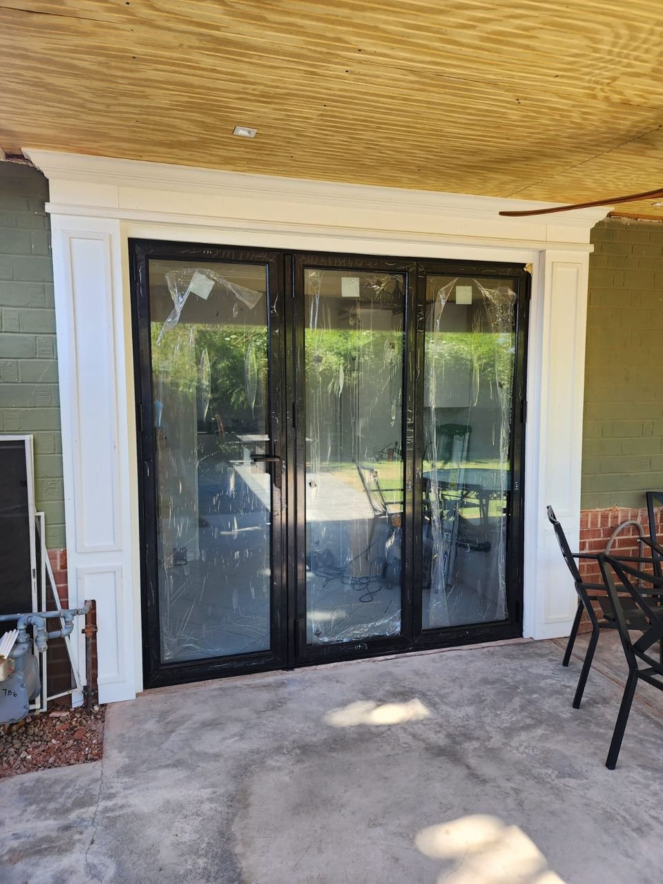 Black three-panel folding door under a covered porch