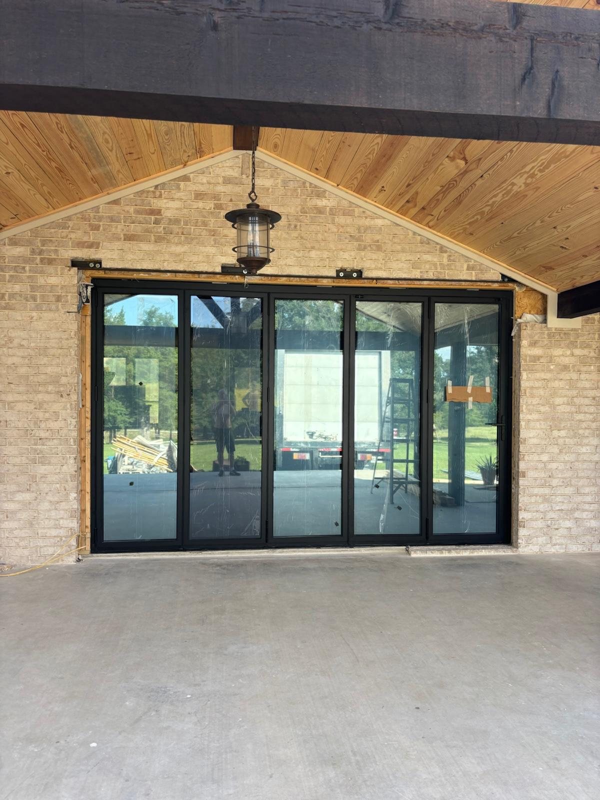 Five-panel black bifold door beneath a cedar gable