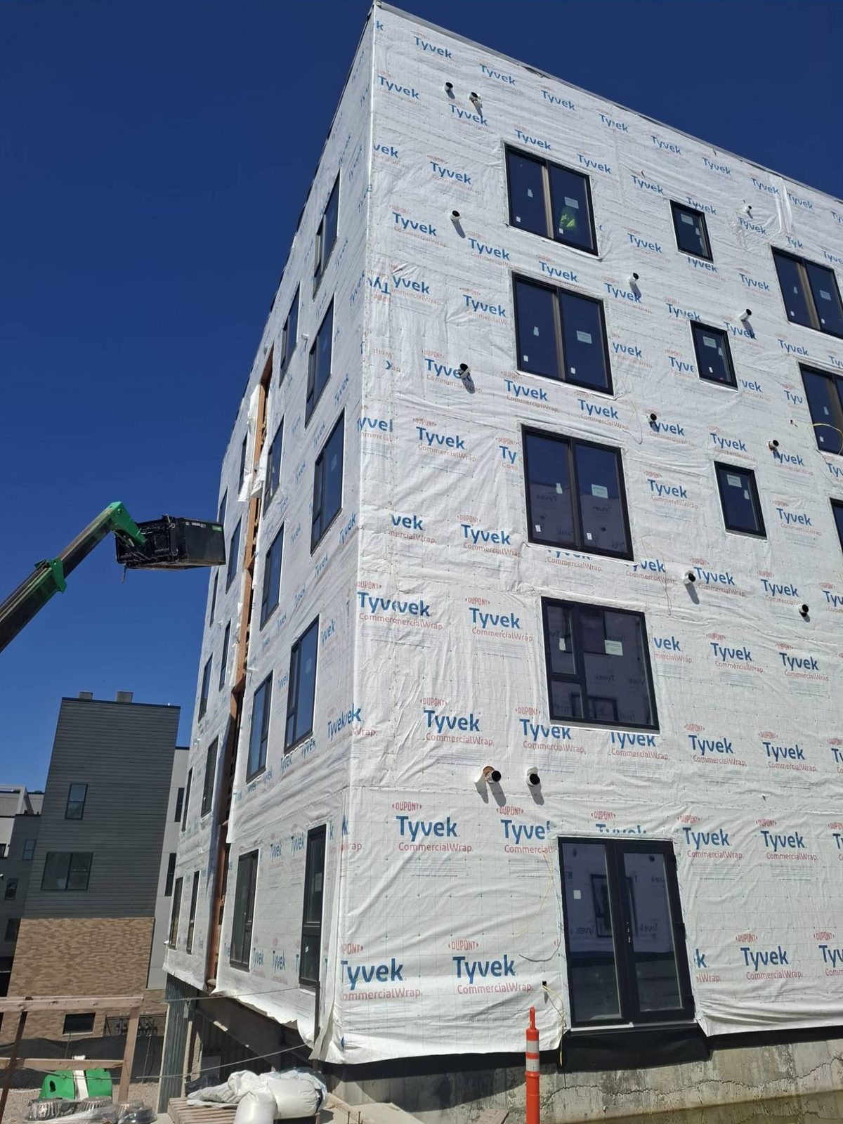 Corner of a multifamily building with stacked black windows and French doors