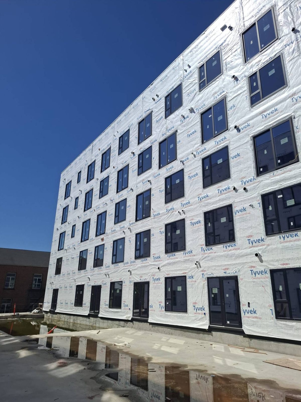 Five-storey multifamily facade with rows of installed black windows and doors