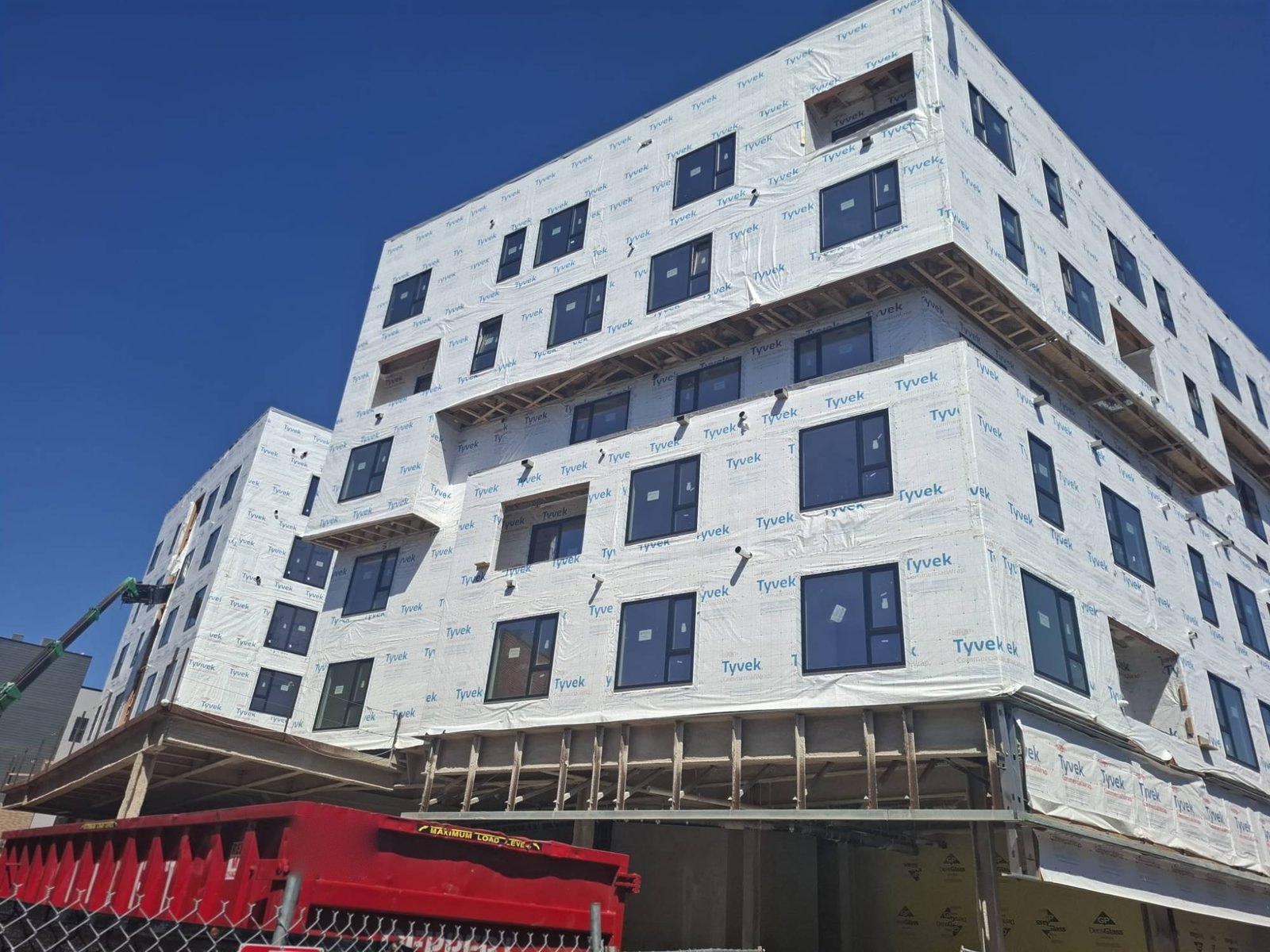 Six-storey multifamily building with black windows set in the weather barrier