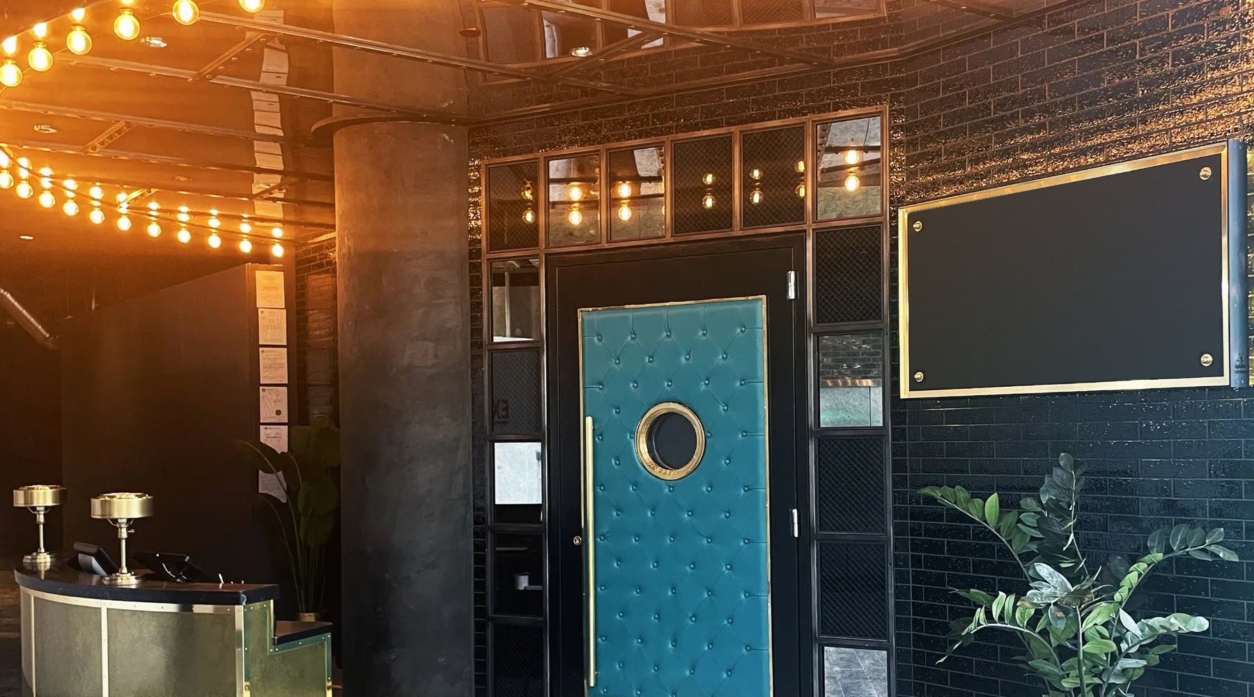 Tufted teal acoustic door with a porthole in a hospitality lounge