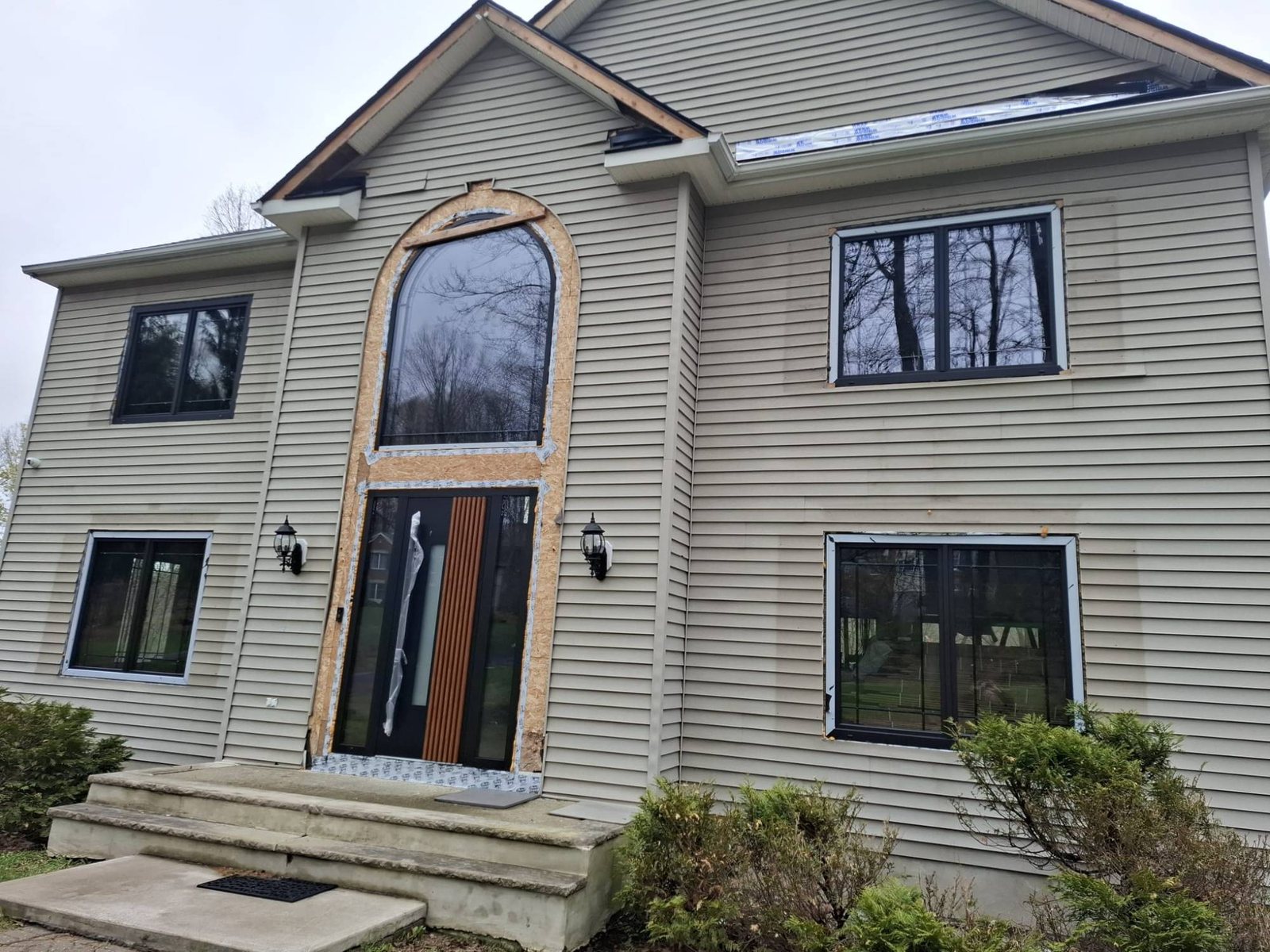 Arched uPVC window over a black and woodgrain entry door with sidelites