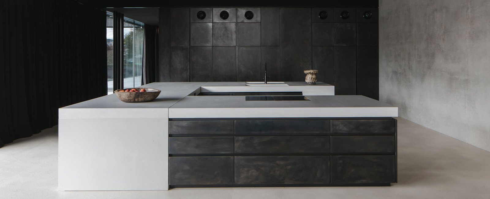 Blackened-steel kitchen with a full-height glass door to the terrace