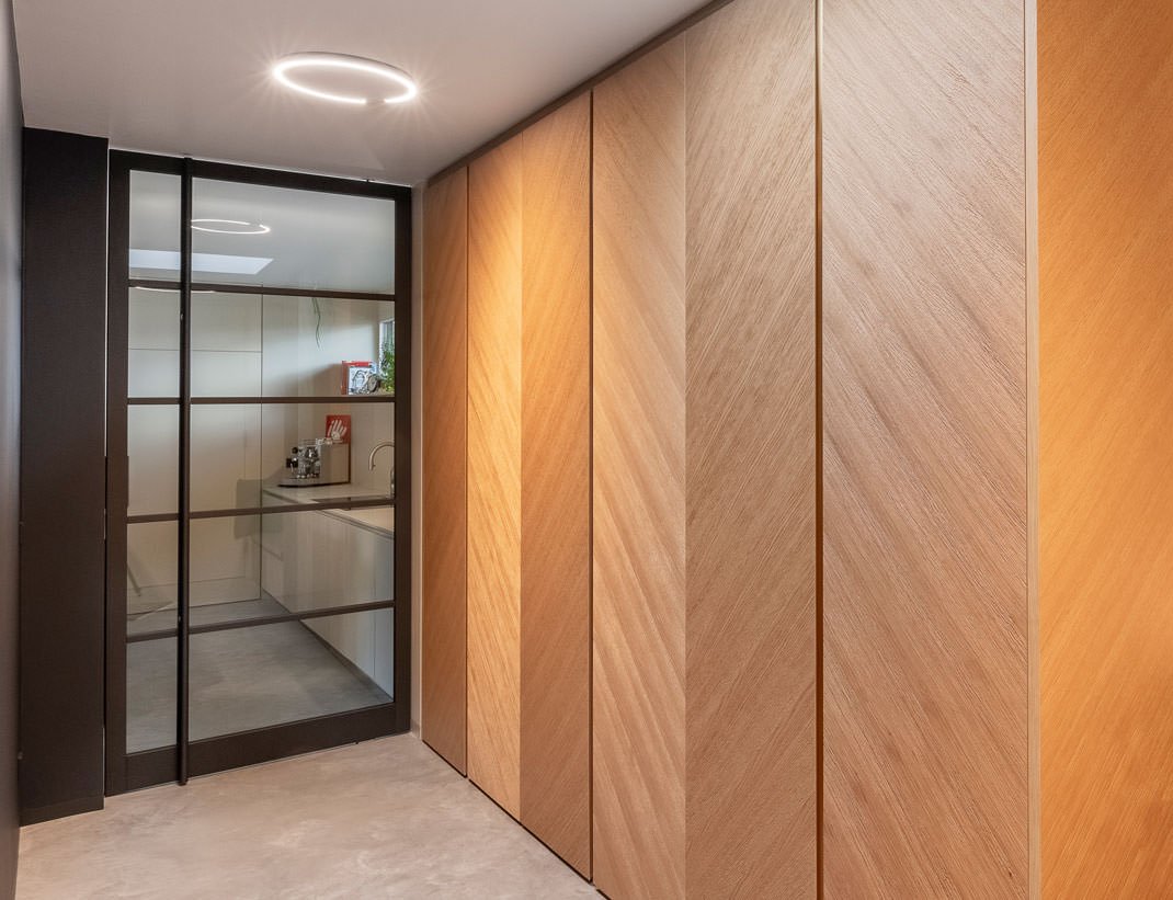 Black steel-framed glass pocket door beside oak cabinetry