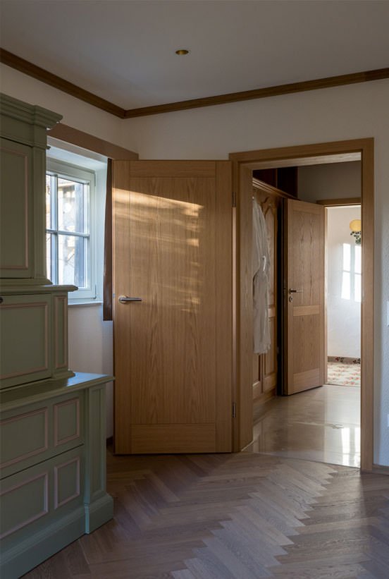 Oak doors opening onto a herringbone-floored hall