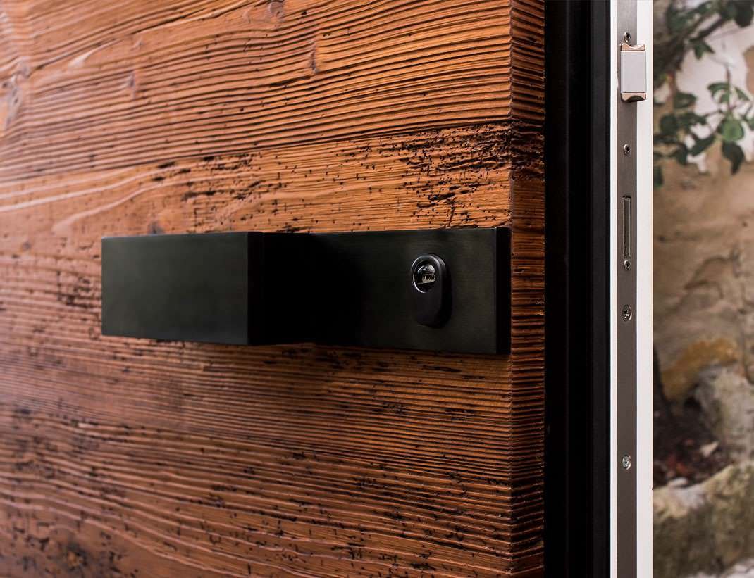 Rough-sawn timber door with a black box pull