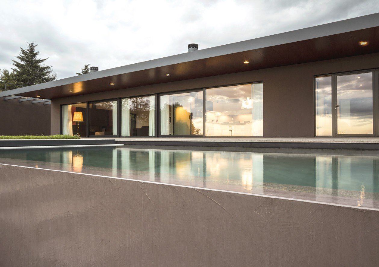 Low villa with steel sliding glass along a reflecting pool