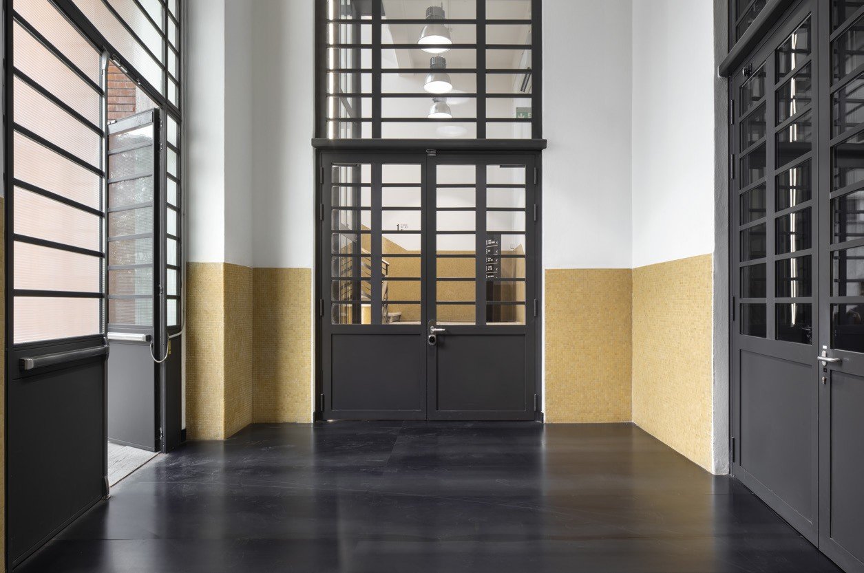 Steel-framed glass doors in a gold-tiled hall
