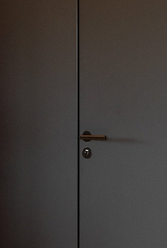 Flush dark door with a bronze lever