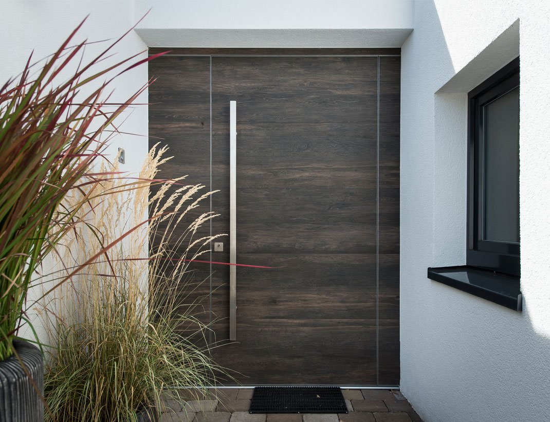 Flush smoked-oak entry door with a full-height stainless pull