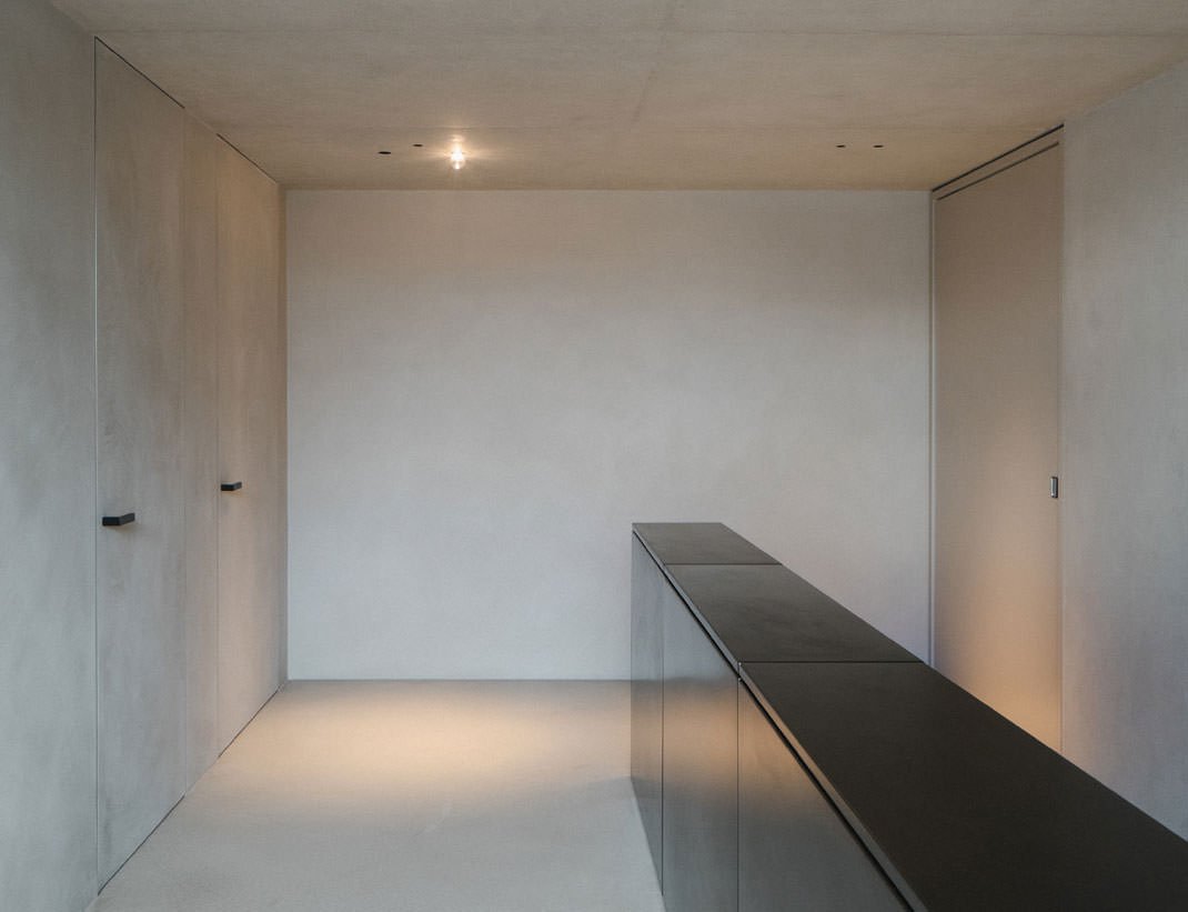 Flush plaster-finish doors in a minimal concrete room